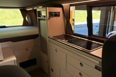 Innenansicht von Campervan mit Bett und Kochnische