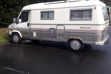 Camper bianco e grigio parcheggiato su una strada bagnata