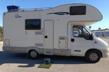 Wohnmobil weiß geparkt unter blauem Himmel