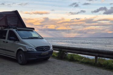 Van camperizzato con tente de toit rivolto verso il mare
