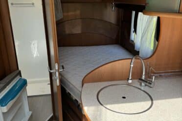 Innenansicht von Wohnmobil mit Bett und Kochnische