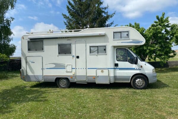 Camping-car blanc stationné sur pelouse verdoyante