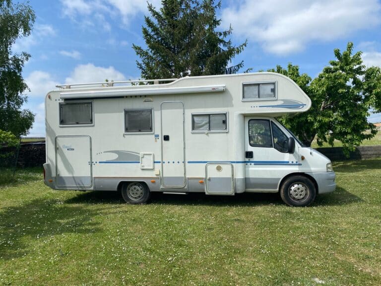 Camping-car blanc stationné sur pelouse verdoyante