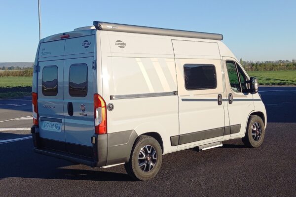 Fourgon aménagé blanc stationné en campagne ensoleillée