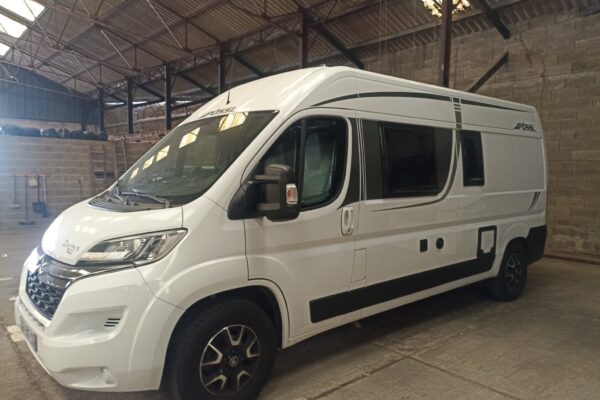 Fourgon aménagé blanc garé dans un entrepôt