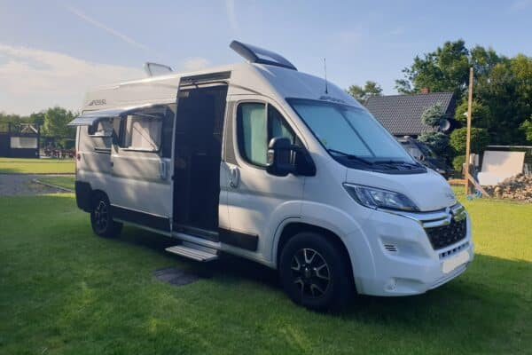 Fourgon aménagé blanc garé sur pelouse ensoleillée