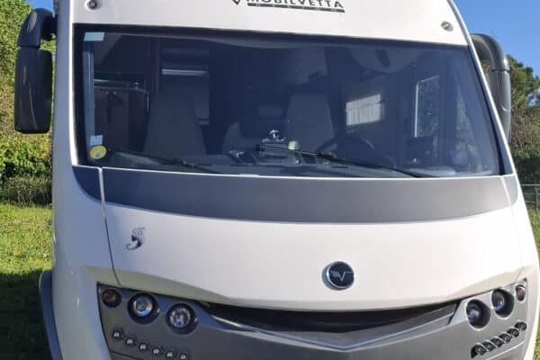 Camping-car Mobilvetta blanc stationné sur pelouse ensoleillée