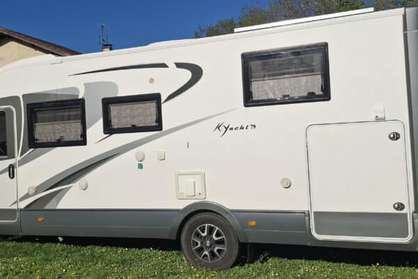Camping-car blanc stationné près d’une maison