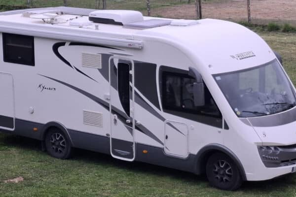 Camping-car blanc stationné sur pelouse verdoyante