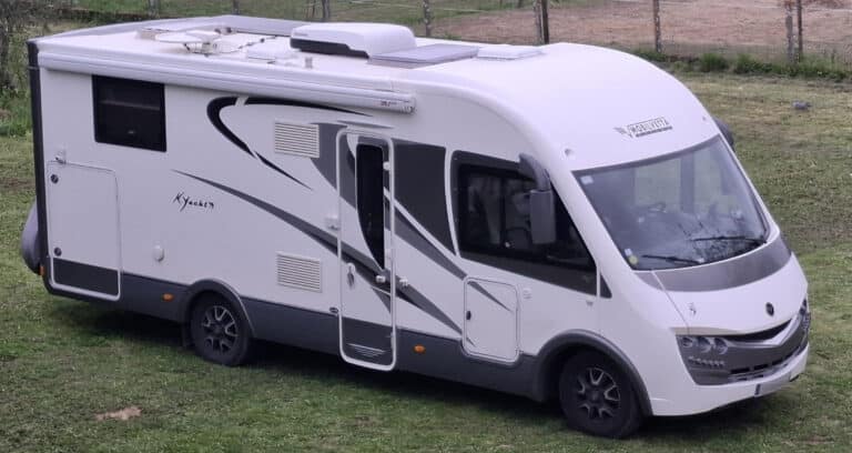 Camping-car blanc stationné sur pelouse verdoyante