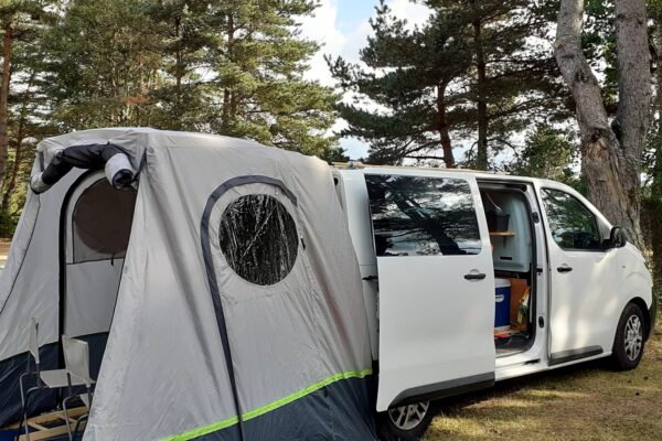 Van aménagé avec tente annexe en forêt