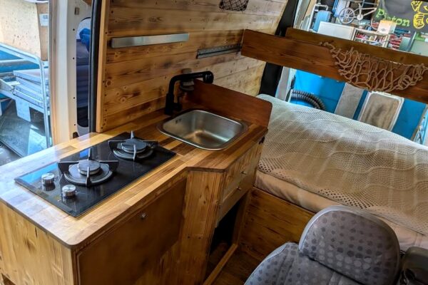 Intérieur van aménagé avec kitchenette et lit en bois