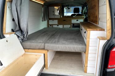 Interno Van camperizzato con letto in legno e spazio di stivaggio