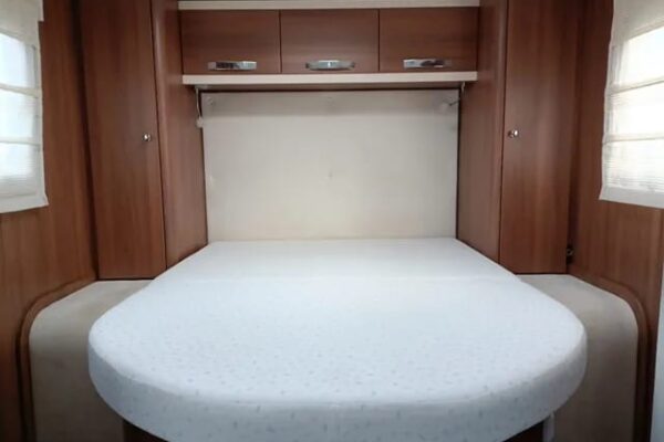 Chambre de camping-car avec lit arrondi et rangements