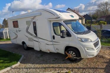 Camper bianco parcheggiato con pattino a rotelle