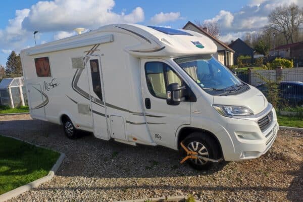 Camping-car blanc stationné avec sabot de roue