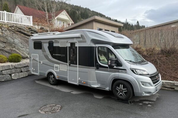 Camping-car gris stationné devant une maison