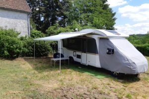 Caravane blanche avec auvent dans un jardin
