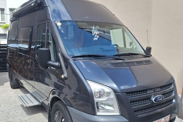 Fourgon aménagé Ford gris stationné en allée