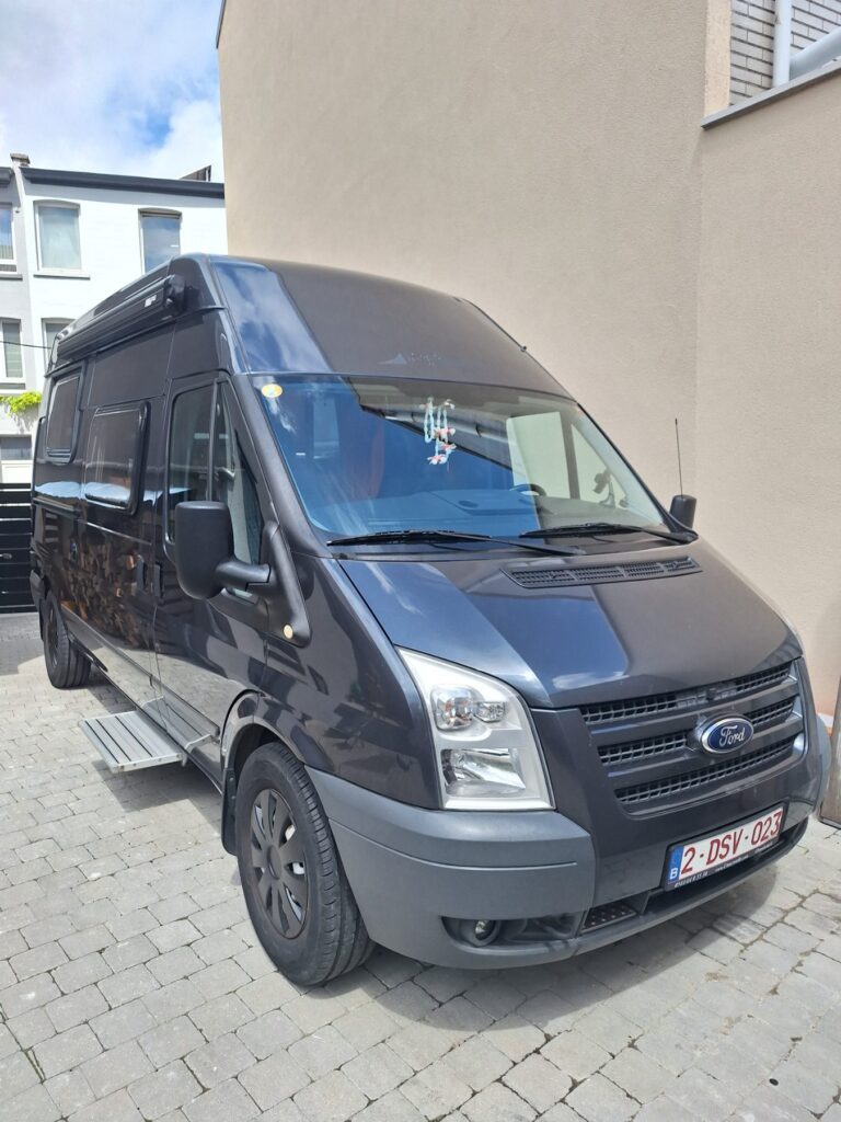 Fourgon aménagé Ford gris stationné en allée