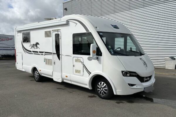 Camping-car blanc stationné devant bâtiment industriel