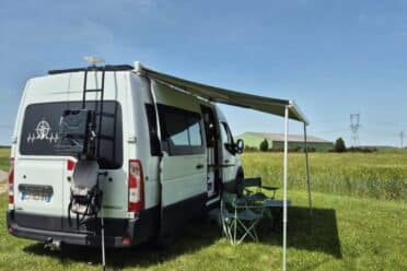 Van camperizzato bianco con tenda da sole in campagna