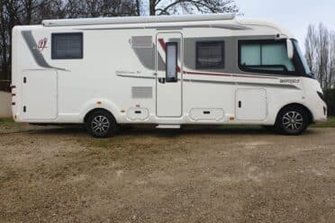 Camping-car blanc stationné sur terrain gravillonné