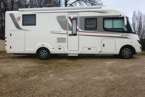 Camping-car blanc stationné sur terrain gravillonné