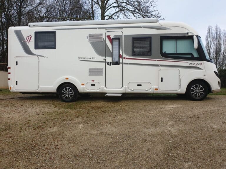 Camping-car blanc stationné sur terrain gravillonné