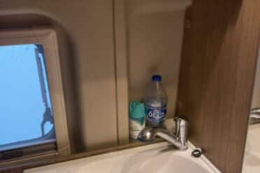 Kleines Waschbecken mit Wasserhahn und Holzregalen