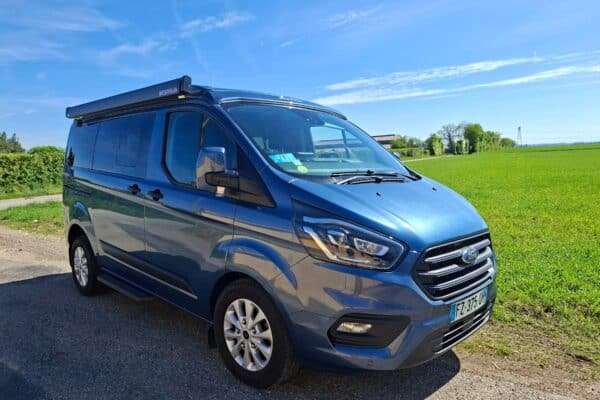 Van aménagé bleu garé en pleine campagne