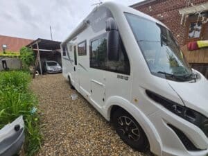 Camping-car blanc stationné dans une cour gravillonnée