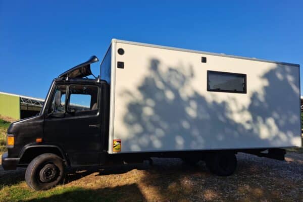 Camion aménagé blanc et noir sous ciel bleu