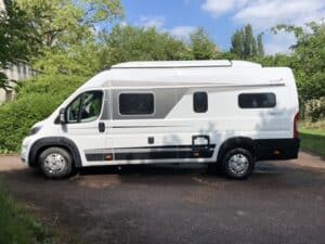 Camping-car blanc stationné dans une allée verdoyante