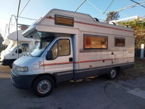 Camping-car blanc stationné en extérieur sous structure métallique