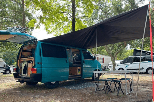Van aménagé avec auvent et table au camping
