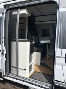 Intérieur aménagé d’un van avec kitchenette et banquettes