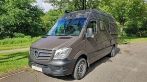 Van aménagé Mercedes marron garé près d’arbres