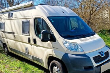 Camping-car Peugeot beige stationné dans un champ