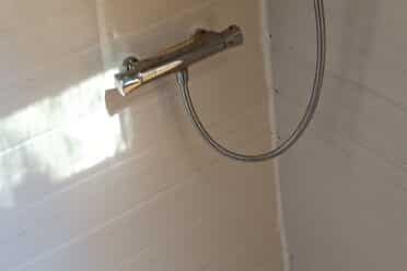 Robinetterie de douche sur carrelage blanc