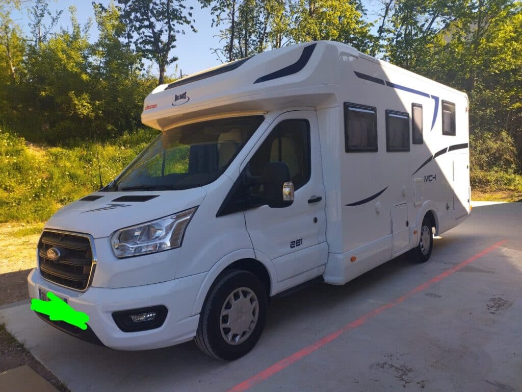 Camping-car blanc stationné près d’arbres