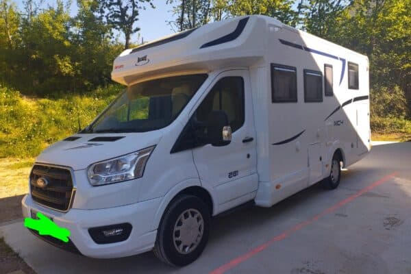 Camping-car blanc stationné près d’arbres