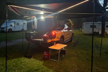 Pick-up 4x4 aménagé sous auvent éclairé au camping