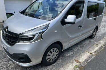 Fourgon Renault gris stationné devant un garage