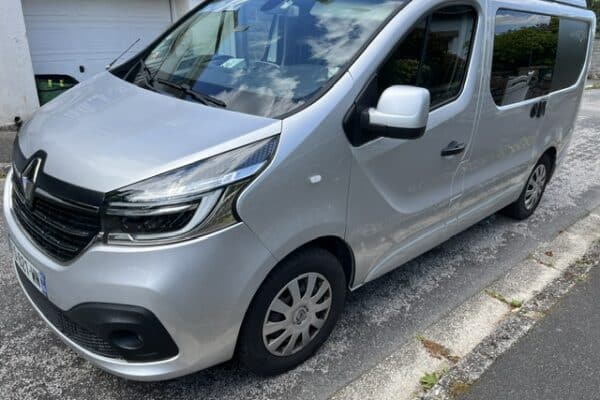 Fourgon Renault gris stationné devant un garage