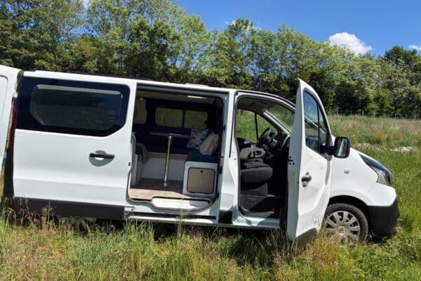 Van aménagé blanc dans un champ ensoleillé
