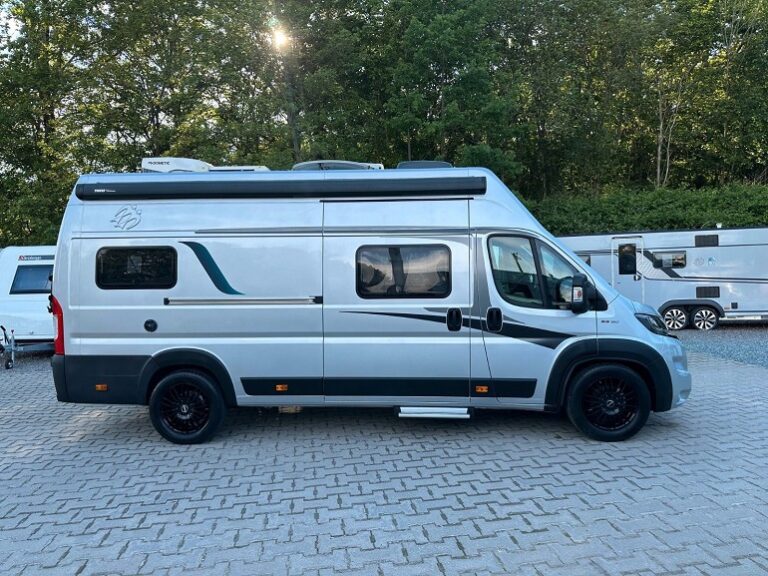 Van aménagé argenté stationné sur parking arboré