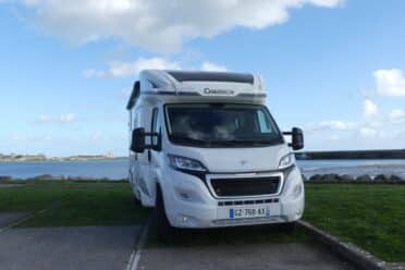 Camping-car blanc stationné près d’un port