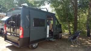 Van aménagé stationné sous des arbres au camping