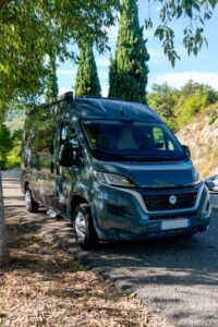 Fourgon aménagé vert stationné sous des arbres